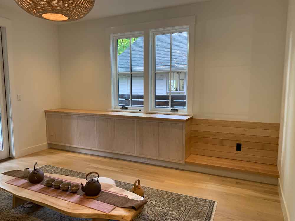 Minimalist Room with Wooden Furniture and Pendant Light Minimalist room with light wood cabinet, bench, patterned rug, coffee table, and woven pendant light.