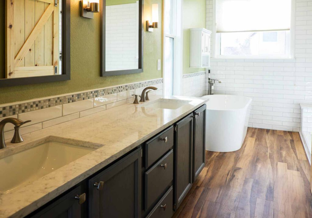Modern bathroom with double sink vanity and freestanding bathtub Bathroom with double sink vanity, dark cabinets, marble countertop, freestanding tub, and wood floor.
