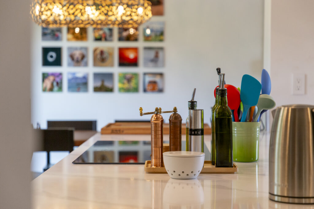 Kitchen counter with spice grinders, utensils, and electric kettle Kitchen counter with spice grinders, oil dispensers, utensils in a green holder, electric kettle, and photo wall.