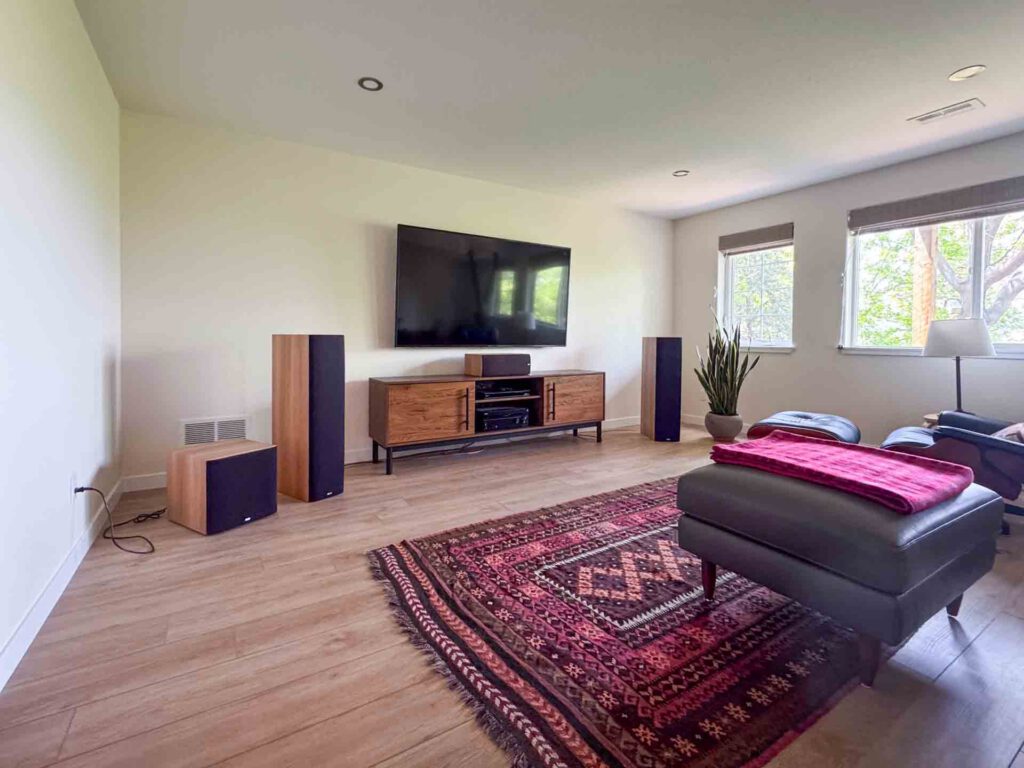 Modern Living Room with Wall-Mounted TV and Leather Seating Living room with wall-mounted TV, wooden media console, floor speakers, leather chair and ottoman.